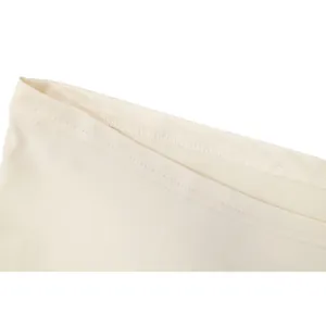 Gros plan sur un tissu crème lisse avec une finition d'ourlet à double surpiqûre soignée