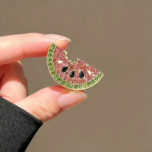 Detailed shot of a sparkling watermelon brooch held in hand, showing crystal details.