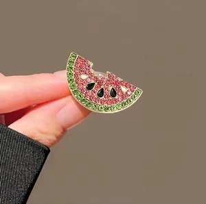 Close-up detail of a sparkling watermelon brooch featuring pink and green crystals