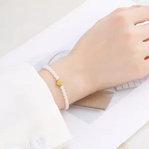 Elegant French vintage pearl bracelet with a golden heart charm on a woman's wrist