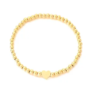 Elegant gold-tone beaded bracelet with a minimalist heart charm on white backdrop