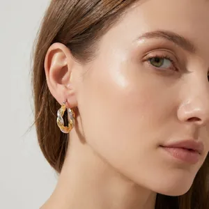 Nahaufnahme eleganter zweifarbiger gedrehter Creolen, die von einem Model getragen werden