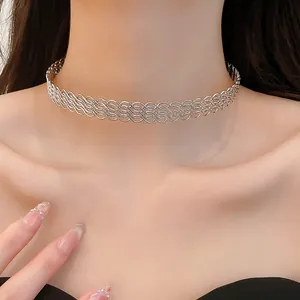 Dettaglio ravvicinato di una collana girocollo in metallo argentato intrecciato a onde