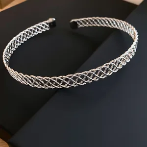 Dettaglio di un choker in metallo argentato a pieghe con un design intrecciato unico