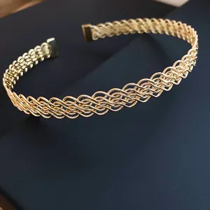Vista dettagliata di un elegante girocollo in metallo dorato con motivo incrociato intrecciato.