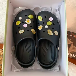 Detailed view of elegant pearl and floral shoe charms on black summer clogs inside a gift box