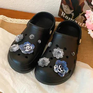 Macro detail of blue and grey 3D flower accessories for clogs mounted on black shoes