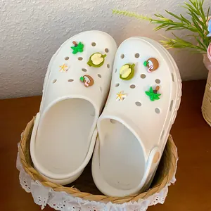 Detail showing tropical fruit and palm tree charms on white clogs in a summer theme