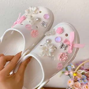 Close-up of DIY clog shoe charms with pink flowers and pearl decorations