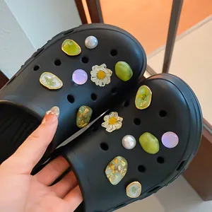 Close-up of elegant floral and pearl charms on black clog shoes for DIY shoe decoration