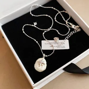 Primer plano del collar con colgante de estrella y perla de estilo francés en caja