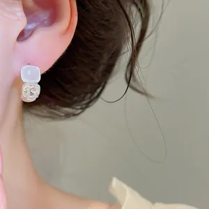 Primer plano de pendientes de plata de estilo francés con piedra blanca lechosa y cristal