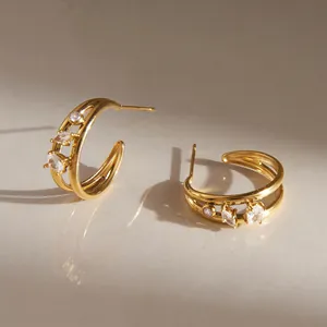 Detailed view of gold C-shaped hoop earrings with marquise and round zircon stones.