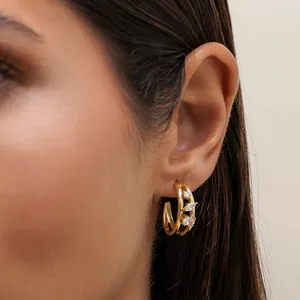 Close-up detail of a gold stainless steel C-shaped hoop earring with sparkling zircons.