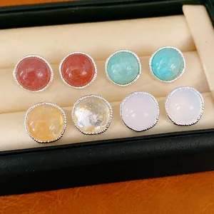 Close-up detail of silver needle round stud earrings with diverse natural stones in box
