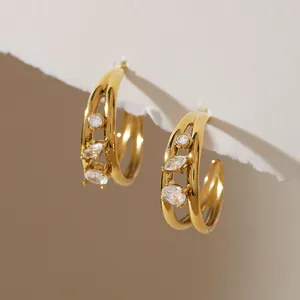Close-up detail of gold titanium steel C-shaped hoop earrings with sparkling inlaid zircons