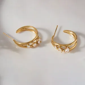 Close-up of gold-plated C-shaped stainless steel earrings with sparkling cubic zirconia
