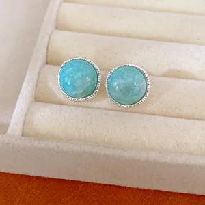Macro detail of elegant silver round stud earrings featuring smooth turquoise gemstones