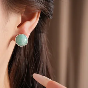 Macro view of an elegant round green stone stud earring with silver bead border detail