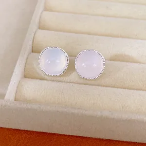 Detailed view of elegant round silver stud earrings with opalescent stones in jewelry box
