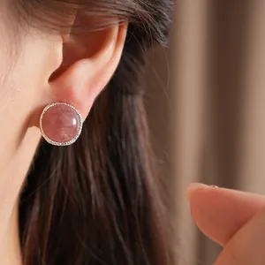 Detailed view of a minimalist round silver stud earring featuring a strawberry quartz stone