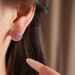 Detailed close-up view of an elegant round pink stone stud earring worn on an ear