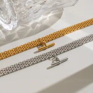 Primo piano di collane in acciaio inossidabile intrecciato oro e argento con pendente a T