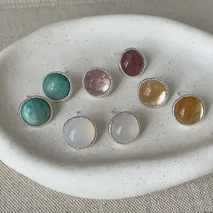 Detailed view of colorful round agate stud earrings with silver textured borders.