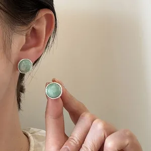 Detailed macro view of retro round green agate stud earrings with silver braided edge