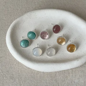 Macro shot of assorted round agate stud earrings arranged on a white ceramic display tray