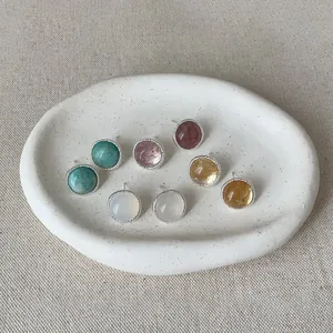 Macro view of vintage round colorful agate stone stud earrings on a white ceramic dish