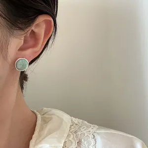 Detailed view of vintage circular stud earring featuring a pale green agate stone
