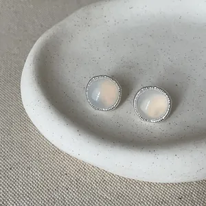 Macro view of vintage round silver stud earrings featuring translucent milky white stones