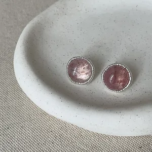 Macro view of retro pink round gemstone stud earrings with silver textured frame on tray