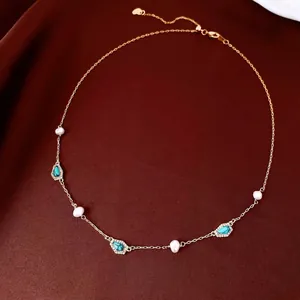 Gold plated necklace with freshwater pearls and turquoise pendants on brown silk background