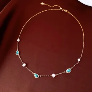 Detailed view of a gold-plated necklace with freshwater pearls and turquoise stones.