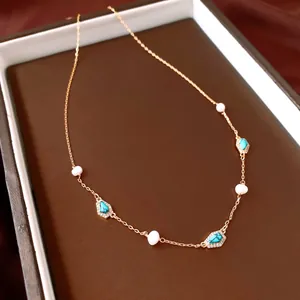 Detailed view of gold-plated necklace with freshwater pearls and turquoise pendants.