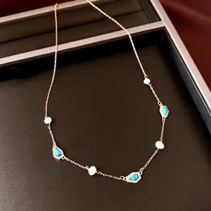 Detailed view of freshwater pearls and turquoise charms on a gold-plated necklace
