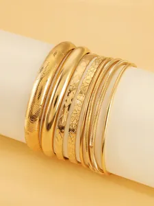 Détail d'un ensemble de bracelets multicouches dorés aux diverses textures géométriques