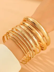 Vue détaillée de bracelets joncs dorés superposés avec divers motifs et textures variés