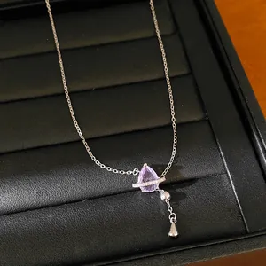 Primo piano di un'elegante collana in argento con ciondolo in zircone viola su vassoio.