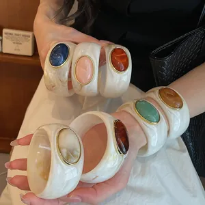 Détail de bracelets luxueux en acrylique marbré ornés de pierres ovales colorées en résine