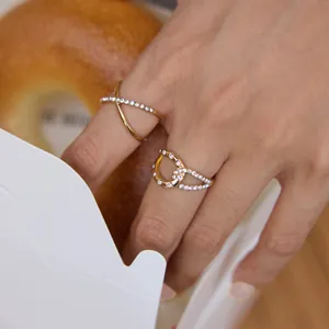 Close-up detail of elegant gold-plated rings featuring white zircon stones worn on hand