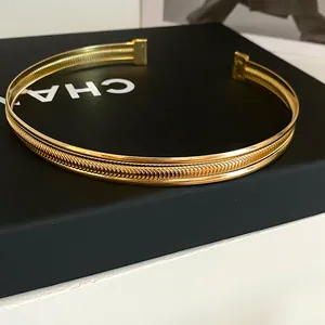 Nahaufnahme eines minimalistischen goldfarbenen geflochtenen Halsreifs auf schwarzem Display