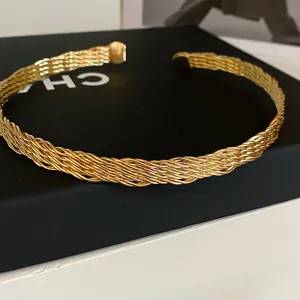 Nahaufnahme eines mehrsträngigen geflochtenen goldenen Metall-Chokers auf einer schwarzen Box.