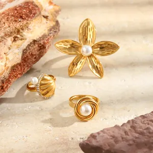Detailed macro view of 18K gold plated stainless steel plumeria and shell rings with pearls