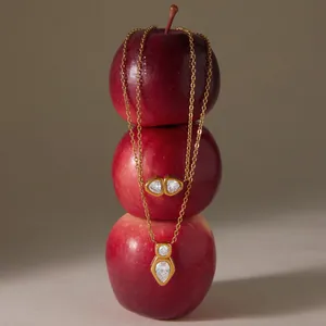 Macro di una collana in acciaio al titanio e zirconi dorata su mele rosse