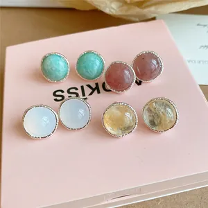 Vista macro de pendientes de botón redondos con piedras de ágata de colores
