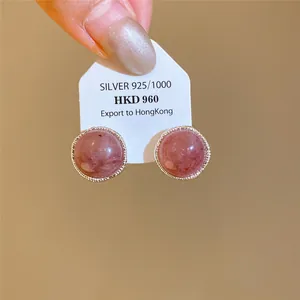 Primer plano de elegantes pendientes redondos de cuarzo fresa y plata con borde texturizado