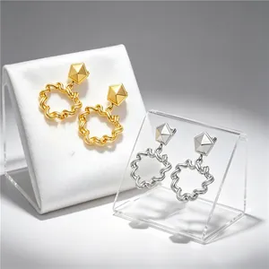 Close-up of gold and silver stainless steel geometric earrings with pleated texture.